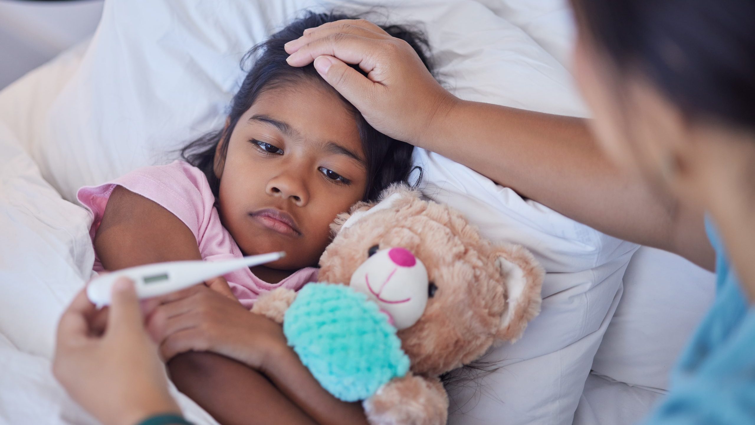 A caretaker gauges the temperature of a sick child.