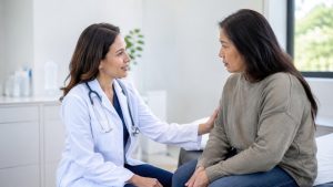 Physician comforts a woman patient in an exam room.