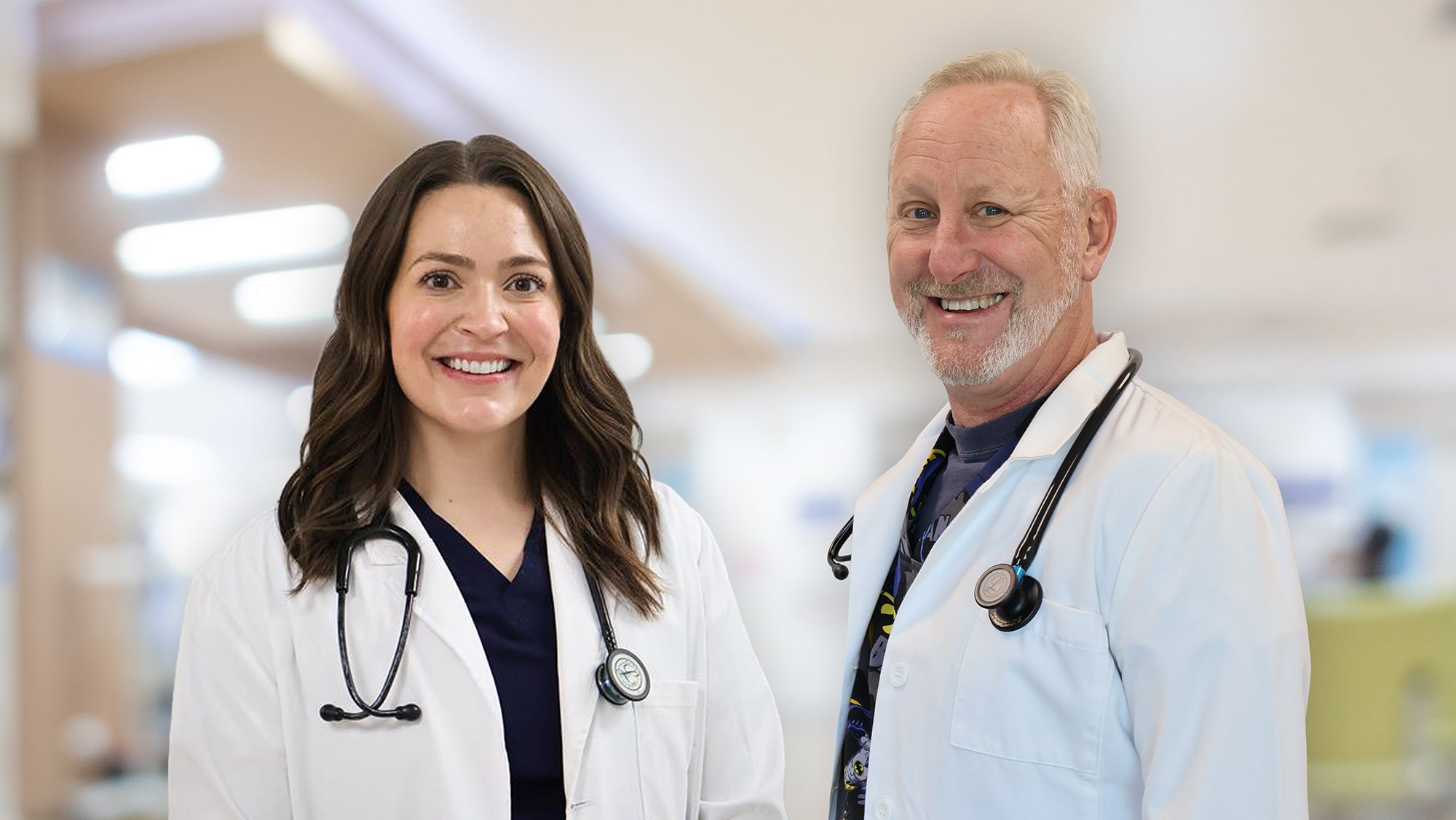 Two physicians in white coats stand side by side against a blurred clincal background